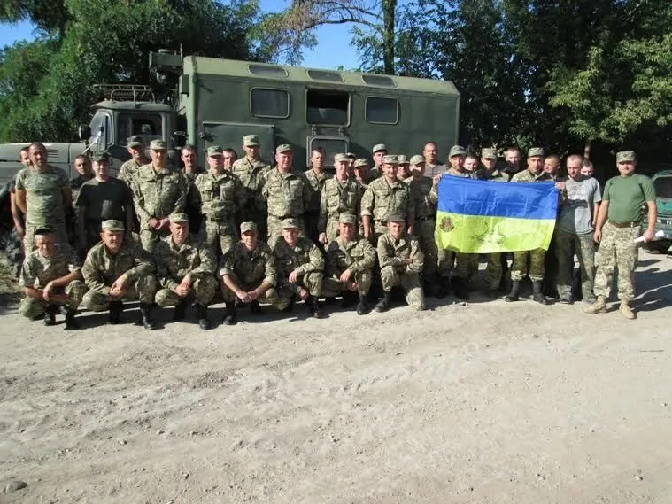 Ukrainian soldiers holding a signed Ukrainian flag